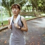 confident woman with towel running in park